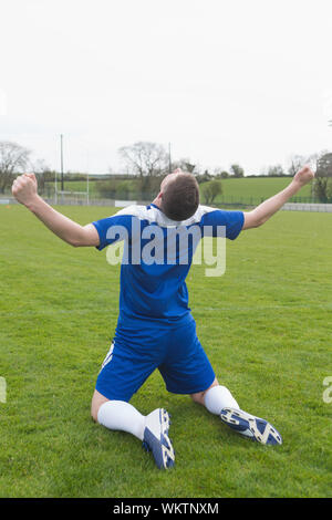 Deluso giocatore di football in blu seduti sul passo dopo aver perso in un giorno chiaro Foto Stock