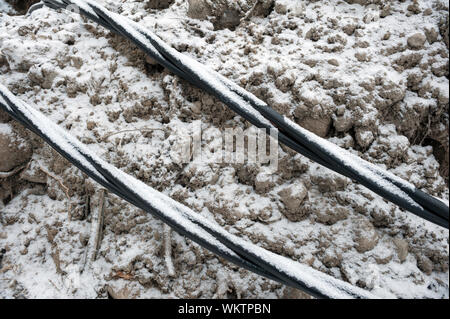 La posa di una fibra ottica e cavi di energia elettrica nel suolo ghiacciato, cavi interrati per internet veloce nella regione rurale - cablaggio sotterraneo in Finlandia Foto Stock