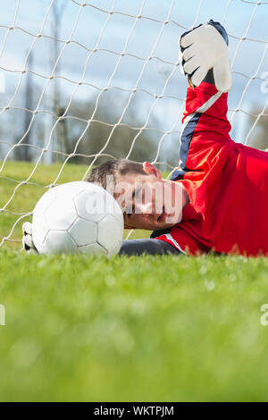 Il portiere in rosso effettuare un salvataggio in un giorno chiaro Foto Stock