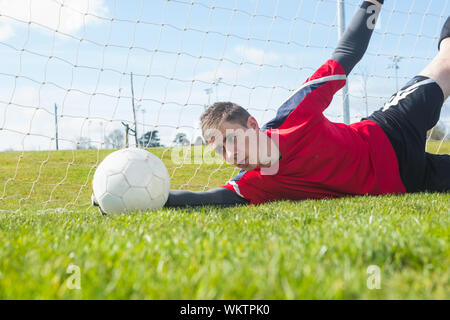 Il portiere in rosso effettuare un salvataggio durante una partita Foto Stock