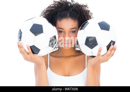 Pretty girl holding palloni da calcio e guardando la fotocamera su sfondo bianco Foto Stock