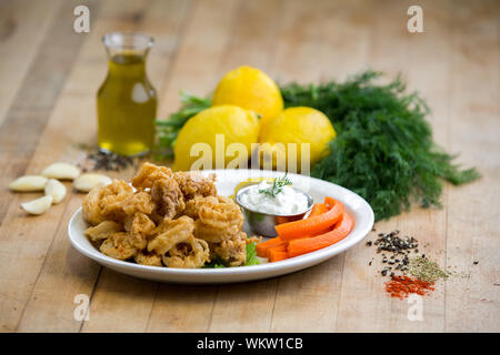 Calamari Antipasto servito su una piastra bianca con limoni e carote Foto Stock