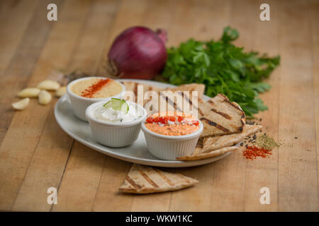 Antipasti greco con olive e salse servita su piatti bianchi con pane pita Foto Stock