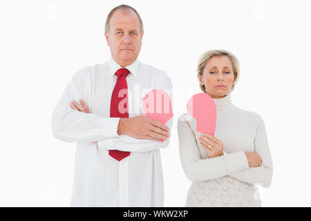 Coppia di anziani in piedi tenendo rotto cuore rosa su sfondo bianco Foto Stock
