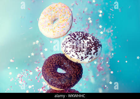 Varie ciambelle decorate in movimento la caduta di dolci e ciambelle colorate Foto Stock