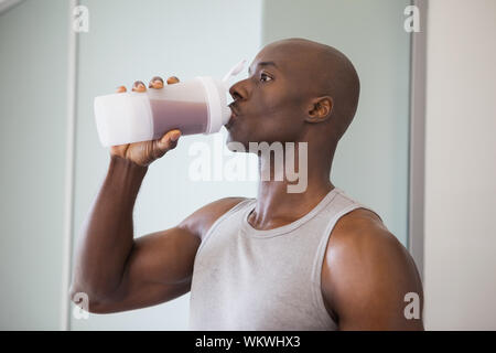 Close-up di un giovane sportivo uomo proteina potabile in palestra Foto Stock