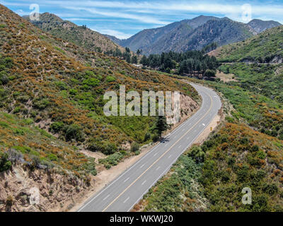 Strada asfaltata si piega attraverso Angeles foreste nazionali di montagna, California, USA. Sottile strada si snoda tra una cresta di colline e montagne in alta quota Foto Stock