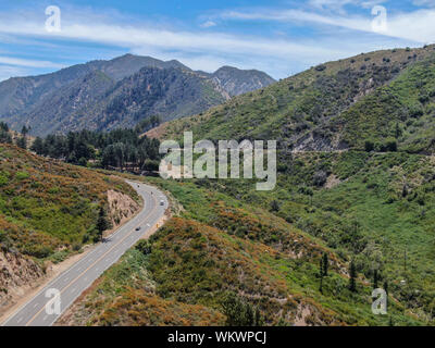 Strada asfaltata si piega attraverso Angeles foreste nazionali di montagna, California, USA. Sottile strada si snoda tra una cresta di colline e montagne in alta quota Foto Stock