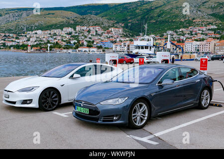 Due Tesla auto elettrica ricarica accanto al mare Adriatico nella città di Senj in Croazia Foto Stock