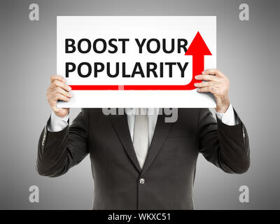 Un business man in possesso di una carta nella parte anteriore del suo volto con il testo aumenta la tua popolarità Foto Stock