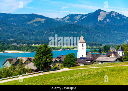 La splendida vista dal Sanktwolfgang im Salzkammergut sulle montagne delle Alpi, case, la chiesa, il lago Wolfgangsee, cielo blu. Salisburgo, Austria Foto Stock
