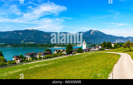 La splendida vista dal Sanktwolfgang im Salzkammergut sulle montagne delle Alpi, case, la chiesa, il lago Wolfgangsee, cielo blu. Salisburgo, Austria Foto Stock