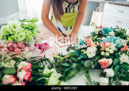 Fioraio donna creazione di composizione floreale in lavoro in studio e scrivere le note. Small business Foto Stock