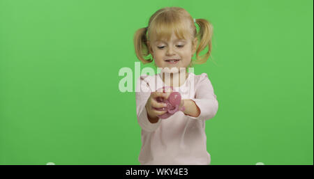 Bambino divertirsi facendo eseguire il ping di limo. Kid giocando con il fatto a mano giocattolo slime. Funny kid ragazza. Relax e soddisfazione. Stranamente soddisfacente melma rosa per puro divertimento e per alleviare lo stress. Schermo verde. Il Chroma Key Foto Stock