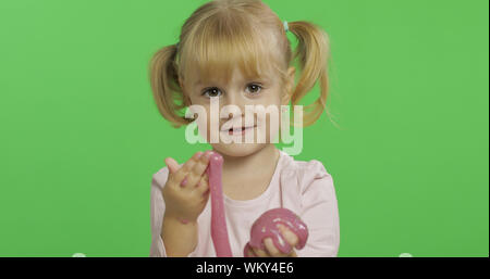 Bambino divertirsi facendo eseguire il ping di limo. Kid giocando con il fatto a mano giocattolo slime. Funny kid ragazza. Relax e soddisfazione. Stranamente soddisfacente melma rosa per puro divertimento e per alleviare lo stress. Schermo verde. Il Chroma Key Foto Stock