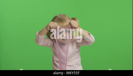 Bambino divertirsi facendo eseguire il ping di limo. Kid giocando con il fatto a mano giocattolo slime. Funny kid ragazza. Relax e soddisfazione. Stranamente soddisfacente melma rosa per puro divertimento e per alleviare lo stress. Schermo verde. Il Chroma Key Foto Stock