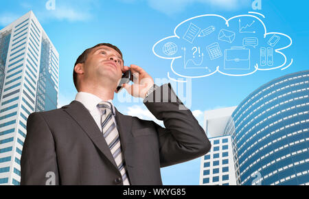 Imprenditore parlando al telefono. Grattacieli e cloud con schizzi di business in background Foto Stock