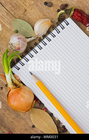 Notebook per scrivere ricette sullo sfondo di un tagliere con spezie Foto Stock