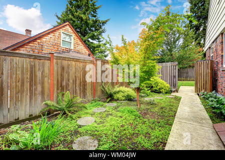 Passerella in cemento che conduce alla zona del cortile. Alta recinzione di legno Foto Stock