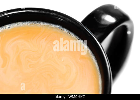 Close-up di una tazza di latte, caffè con panna o latte vortici in una tazza nera isolati su sfondo bianco. Foto Stock