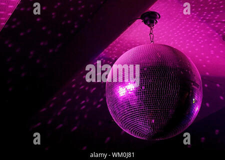 Palla da discoteca in movimento che riflette luce rosa nel night club con copy-spazio Foto Stock