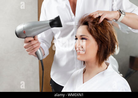 Vista ritagliata del parrucchiere womanÕs di asciugatura dei capelli. Vista laterale Foto Stock