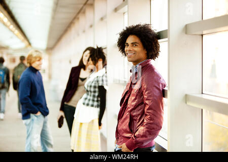 Un americano africano maschio con amici parlando in background Foto Stock