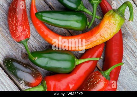 Cumulo di colore rosso e verde Habanero e Jalapeño Chili Peppers isolate su legno rustico sfondo. Vista superiore Foto Stock