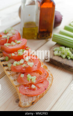 Baguette alla griglia con pomodori grigliati, olio di oliva e di sedano tagliato Foto Stock