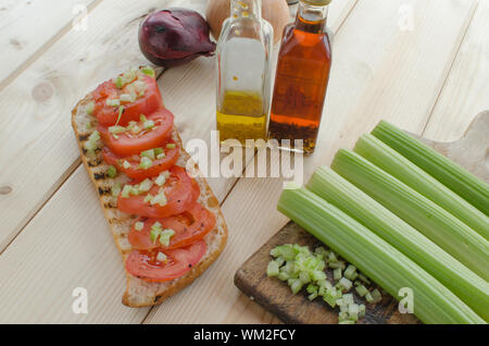 Baguette alla griglia con pomodori grigliati, olio di oliva e di sedano tagliato Foto Stock