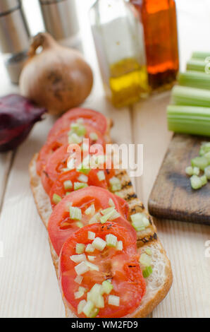 Baguette alla griglia con pomodori grigliati, olio di oliva e di sedano tagliato Foto Stock