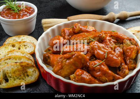 Hot ali di pollo con il piccante salsa habanero e insalata mista con pomodorini e grigliate di baguette con olio d'oliva Foto Stock