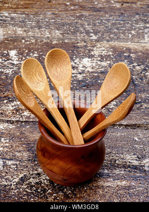 Cinque piccoli cucchiai di legno nel recipiente isolato sul rustico sfondo di legno Foto Stock