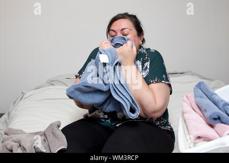 Felice latina donna detiene una fresca Salvietta ripiegata al suo naso e odori Foto Stock