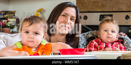 Una madre in cucina pone con neonati Foto Stock