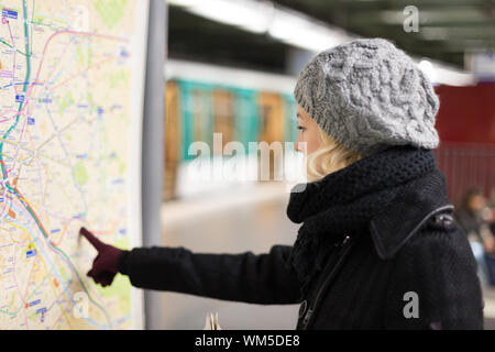 Signora guardando la mappa dei trasporti pubblici pannello. Foto Stock