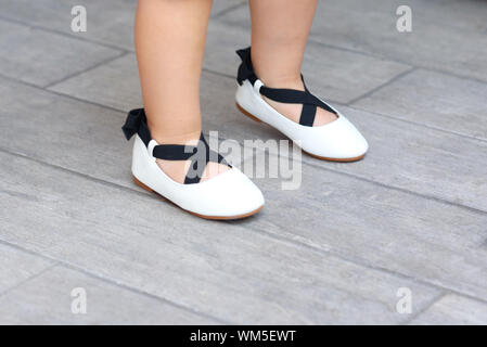 Close up carino bambina per le gambe in nuovi appartamenti. Bambina in una calzatura store. Il Toddler kid giocando ed esecuzione cercando ballerina scarpe in un supermercato. Foto Stock