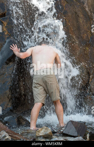 Escursionista il raffreddamento in una cascata, Wallowa Mountains, Oregon. Foto Stock