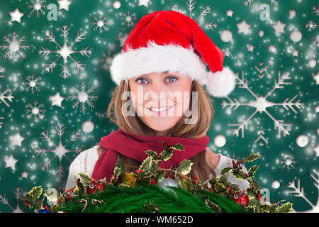 Festive bionda sorridente in telecamera contro il simbolo del fiocco di neve pattern di sfondo Foto Stock