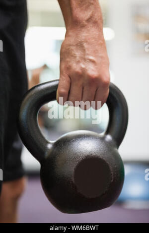 Close up di un uomo ritagliata holding bollitore campana in palestra Foto Stock