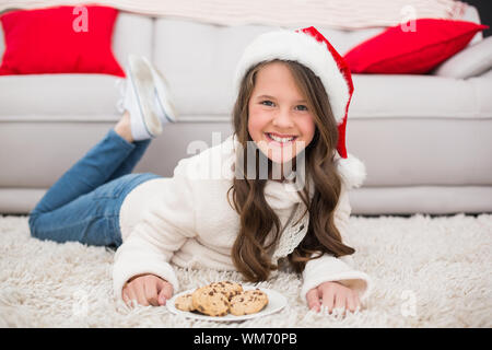 Festive bambina di mangiare i cookie in casa nel salotto Foto Stock