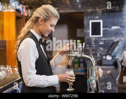 Barista tirando un bicchiere di birra in un bar Foto Stock