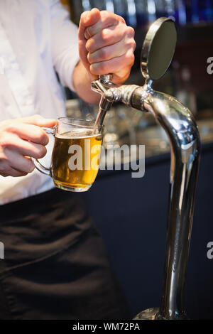 Bello barman tirando una pinta di birra in un bar Foto Stock