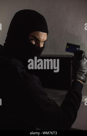 Hacker tramite carta di debito e laptop in casa Foto Stock