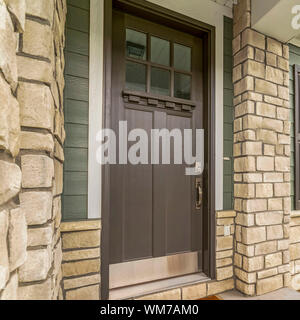 Home quadrato entrata con una vetrata in vetro marrone porta in legno e pietra e parete di mattoni Foto Stock