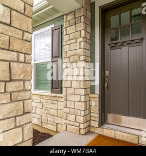 Cornice quadrata Home ingresso con una vetrata in vetro marrone porta in legno e pietra e parete di mattoni Foto Stock