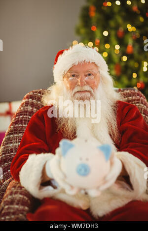 Babbo Natale offrendo salvadanaio a casa nel soggiorno Foto Stock