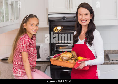 Felice madre e figlia in posa con il tacchino arrosto a casa in cucina Foto Stock