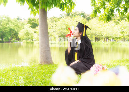 Belle Donne asiatiche laurea diploma di contenimento con orgoglio e sorridente in un abito di accademico.Congratulazioni felicità studentessa indossando la graduazione Foto Stock
