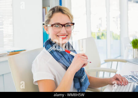 Editor segna il foglio di contatto e guardando la telecamera in ufficio Foto Stock